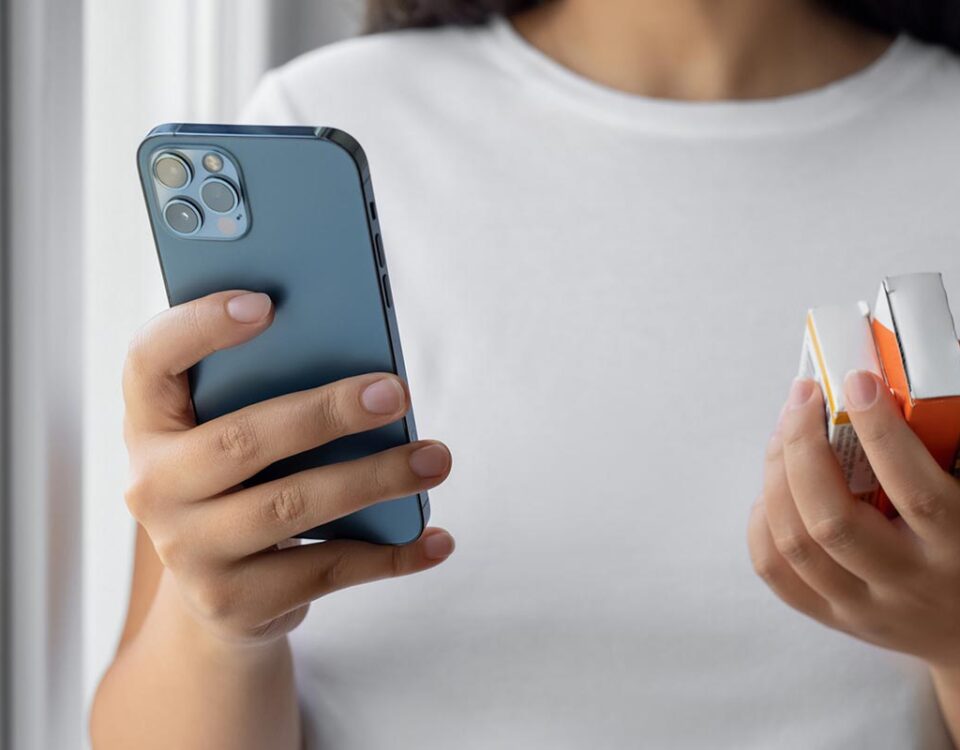 Mulher consultando informações sobre medicamentos com celular