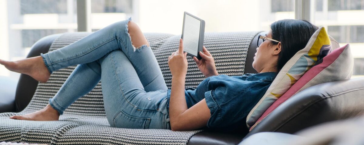 Mulher deitada lendo ebook