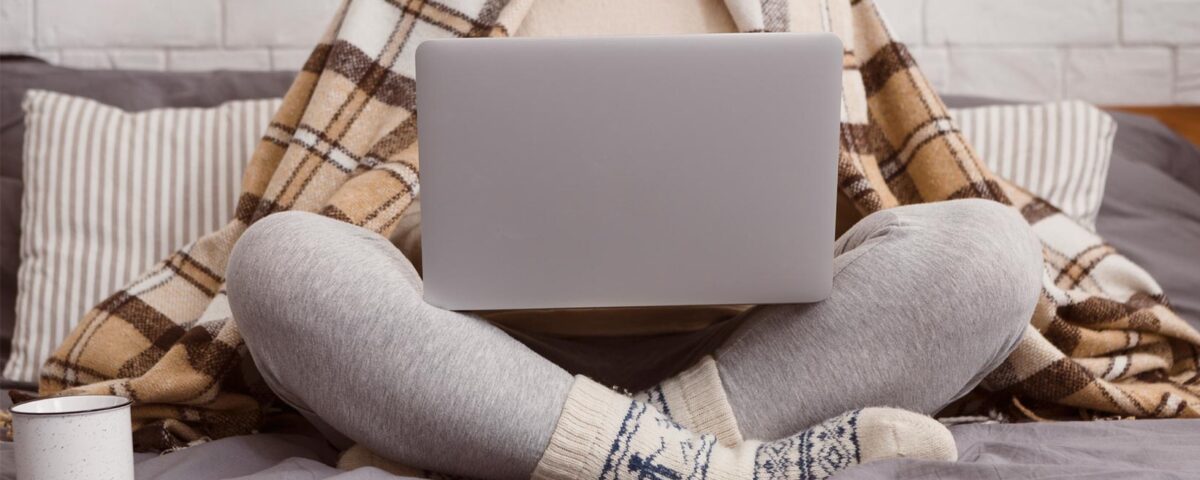 Mulher sentada com roupas de frio utilizando um computador