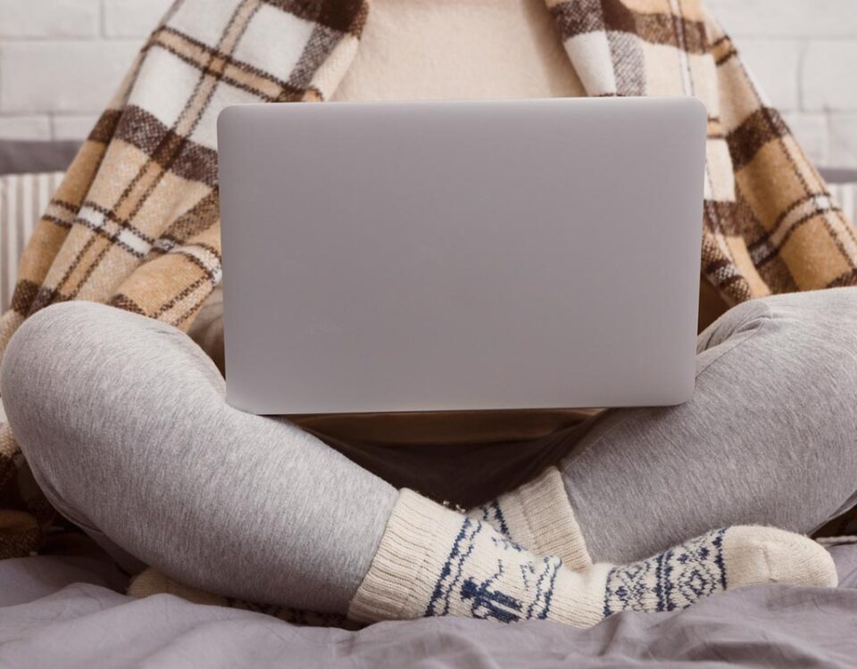 Mulher sentada com roupas de frio utilizando um computador