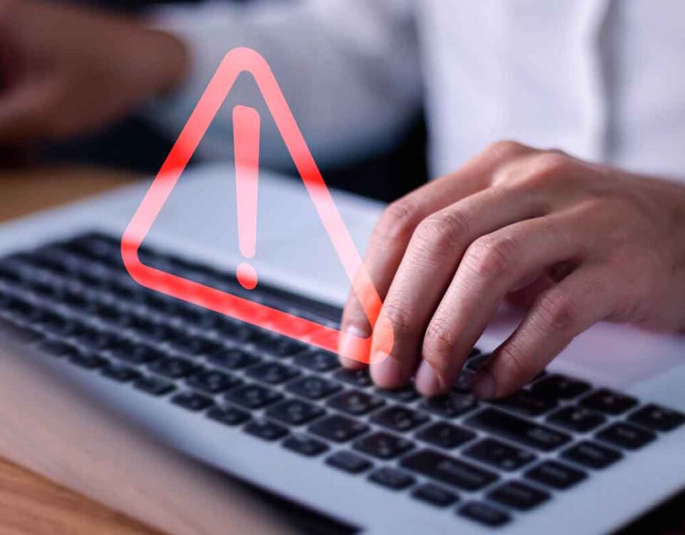 Pessoa mexendo em notebook e sinal de alerta por causa de cuidado com falsas informações