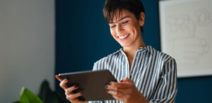 Mulher sorrindo ao ler um com conteúdo em saúde