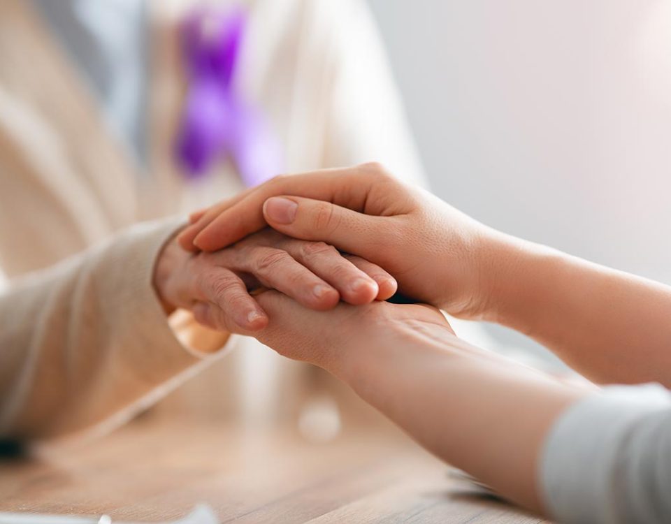 Mulher com laço roxo sendo pega com as mãos de outra pessoa